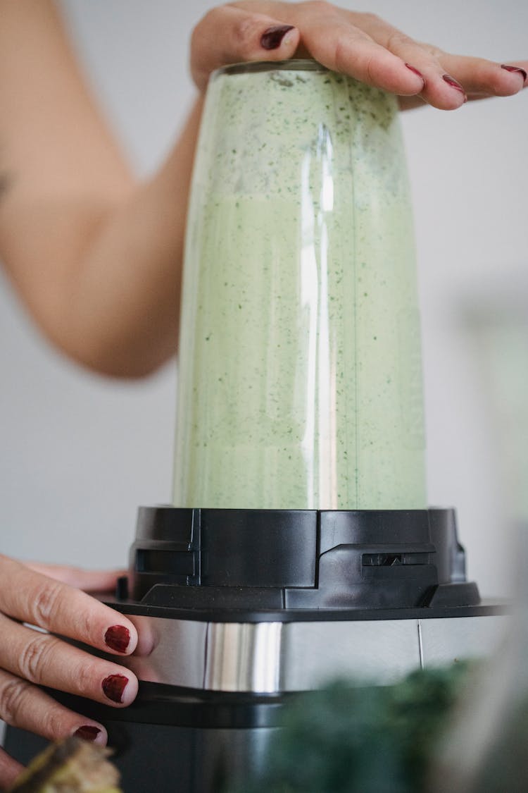 A Person Making Smoothie Using A Blender