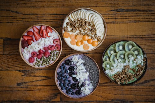 Free Oatmeal Breakfast Bowls with Various Fruits on a Table Stock Photo