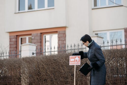 A Woman in Black Jacket Looking at the Sign on the Street