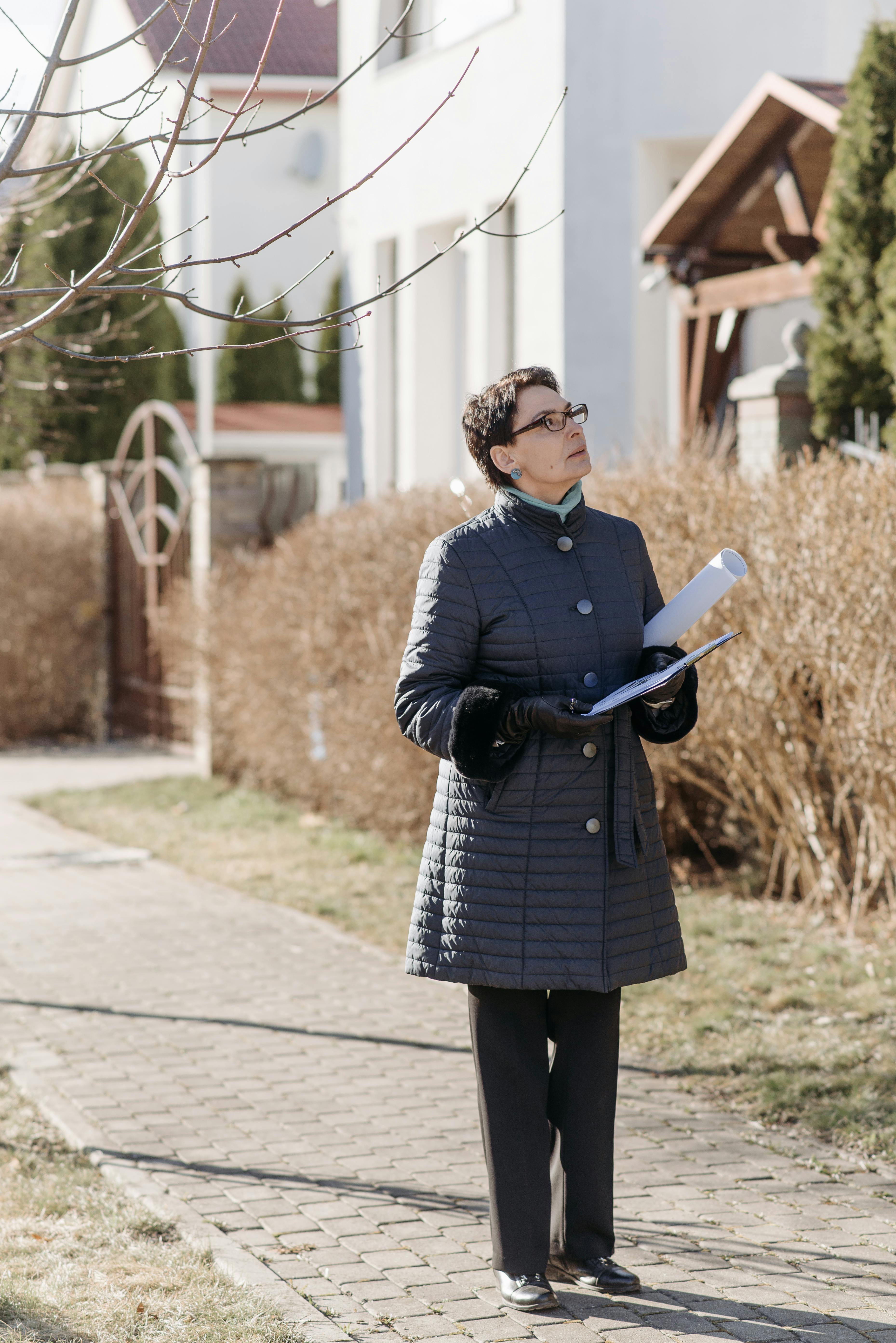 woman in blue coat standing on sidewalk