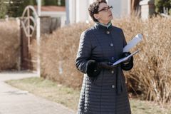 Professional real estate agent observing a property outdoors in winter.