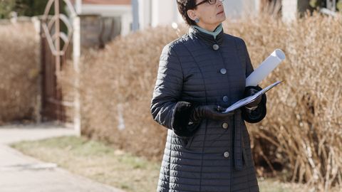 Professional real estate agent observing a property outdoors in winter.