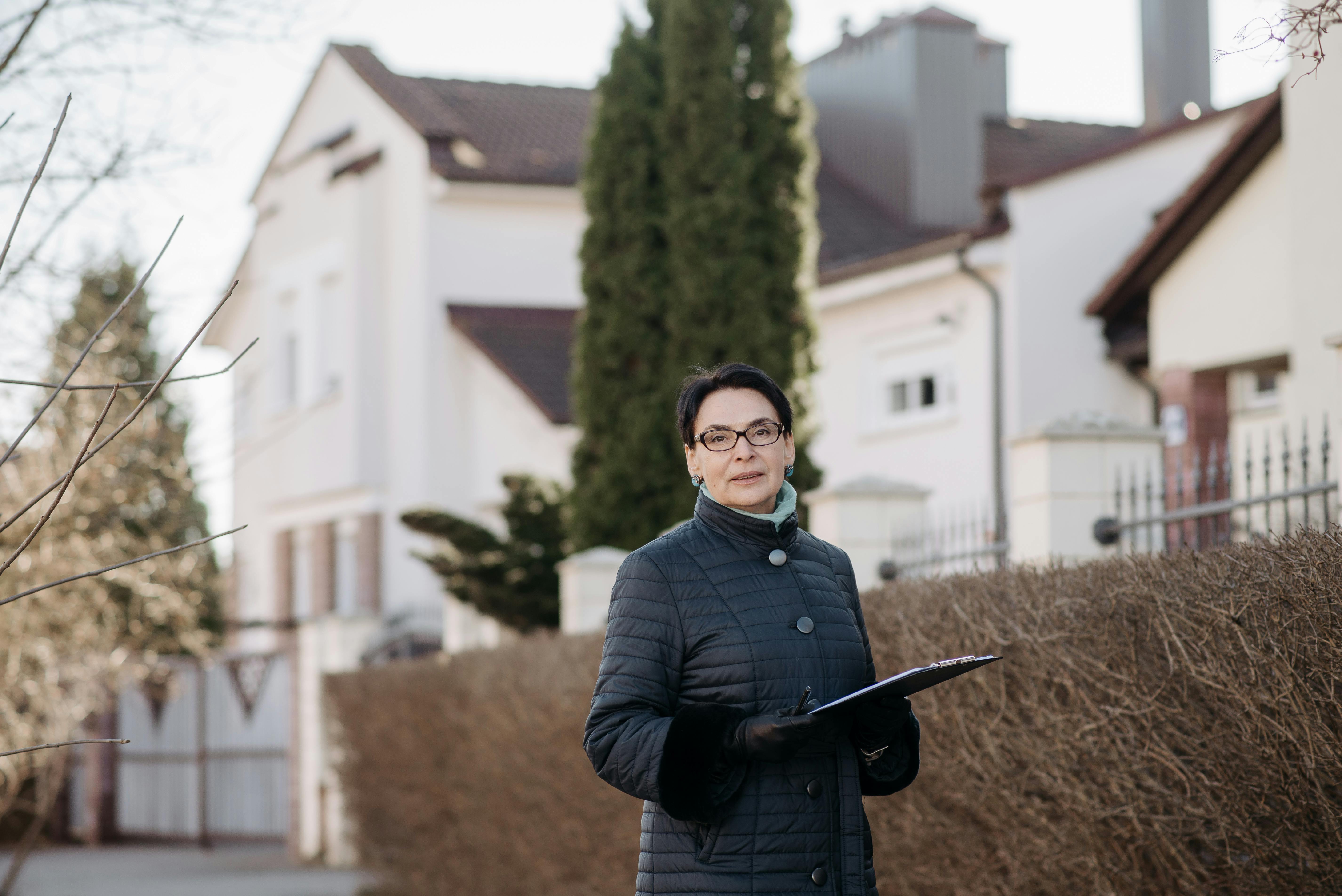 Adult woman in eyeglasses standing outside holding a clipboard, ideal for business or lifestyle themes.