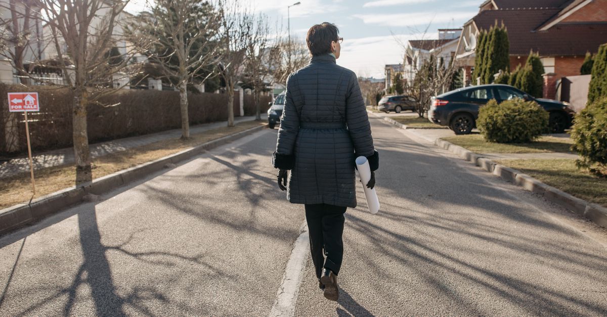 Back view of a woman walking down a suburban street on a sunny winter day.