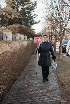 Real estate agent walking on a path, holding a 'For Sale' sign.