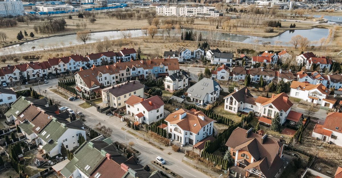 Aerial photography capturing a vibrant suburban neighborhood with distinct red-roofed houses and surrounding greenery.