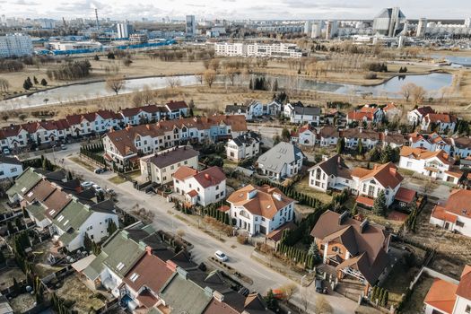 Aerial photography capturing a vibrant suburban neighborhood with distinct red-roofed houses and surrounding greenery.