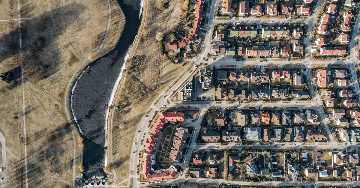Drone shot of a suburban residential area with roads and houses alongside a river.