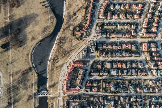 Drone shot of a suburban residential area with roads and houses alongside a river.