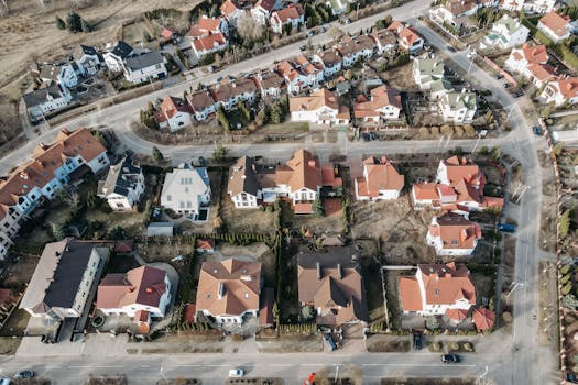 High-angle aerial view of urban residential area with red-roofed houses and winding roads.
