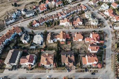 Free High-angle aerial view of urban residential area with red-roofed houses and winding roads. Stock Photo