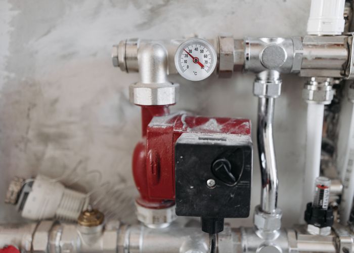 Pressure gauge and pipes in a plumbing mechanical room
