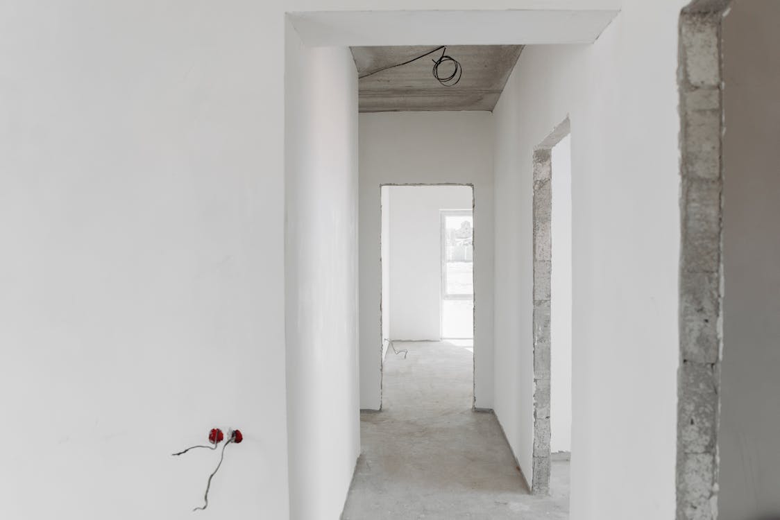 vu d'un couloir de maison peint en blanc avec prises apparentes en cours de travaux 