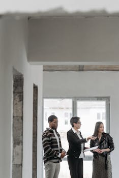 Real estate agent showing a house to diverse clients indoors, discussing property details.