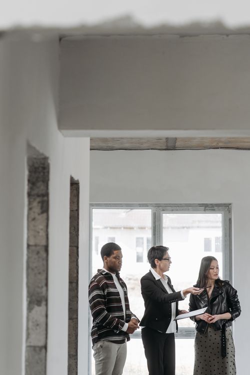 Free Real estate agent showing a house to diverse clients indoors, discussing property details. Stock Photo