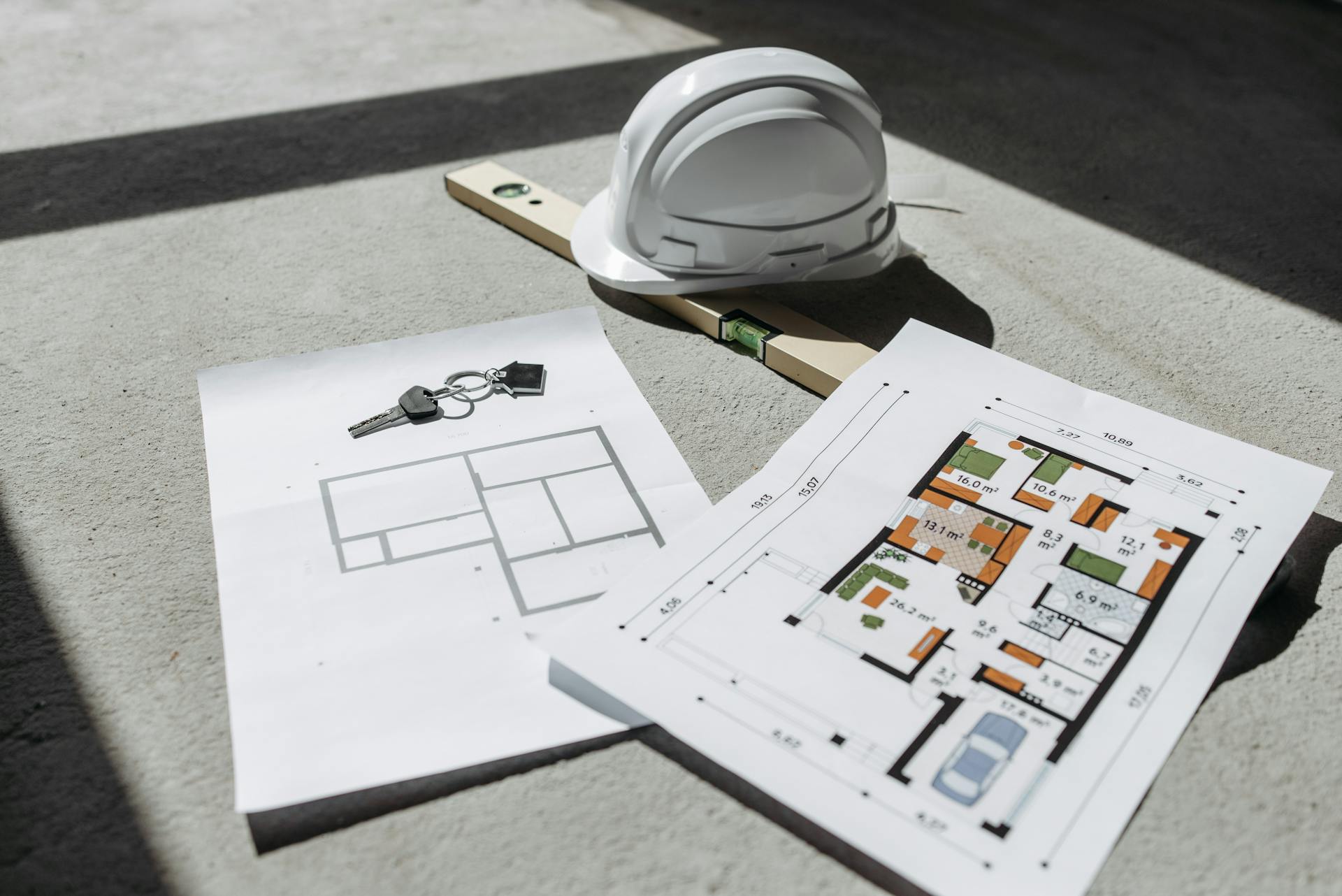 Architectural floor plans with helmet and keys on sunlit floor, perfect for real estate or construction themes.