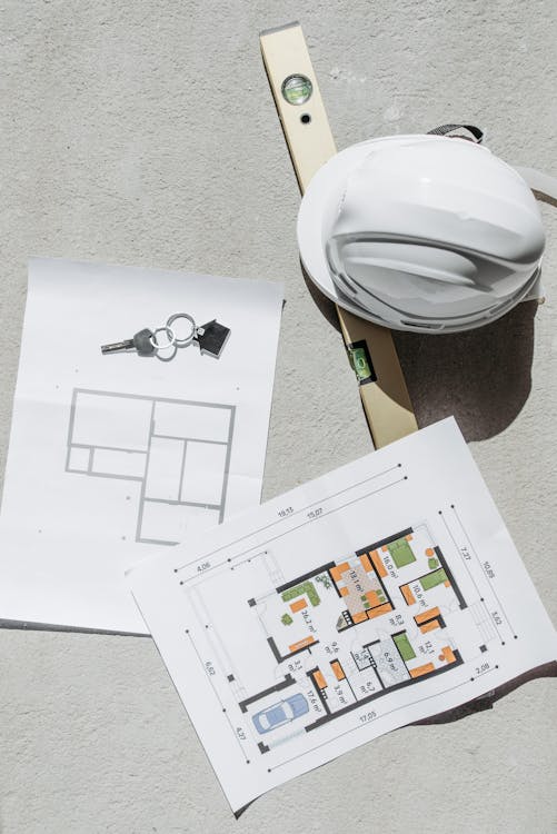 Free White Hard Hat Beside Floor Plans and House Key Stock Photo