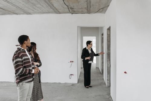 Free A couple explores an unfinished apartment with a real estate agent, considering property purchase options. Stock Photo