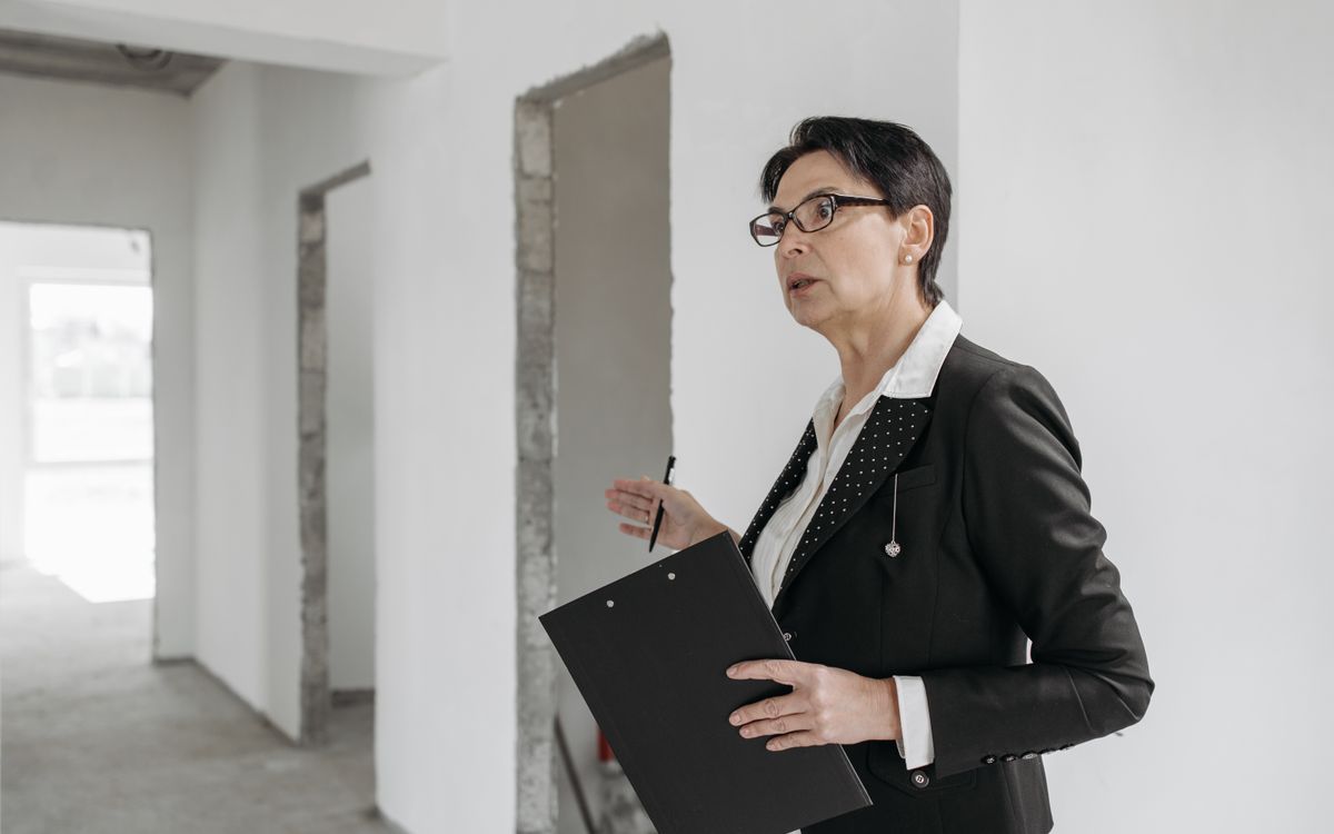 Professional woman in a suit holding a clipboard while inspecting an interior space