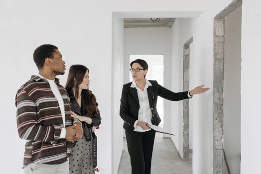 Real estate agent shows a house to a couple, discussing features.