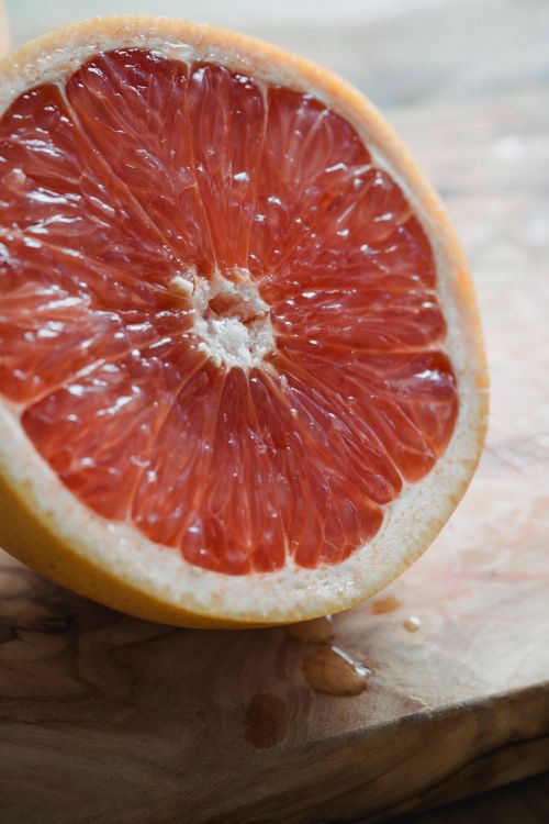 Free Close-up of a juicy grapefruit half on a wooden cutting board, showcasing its vibrant color and texture. Stock Photo