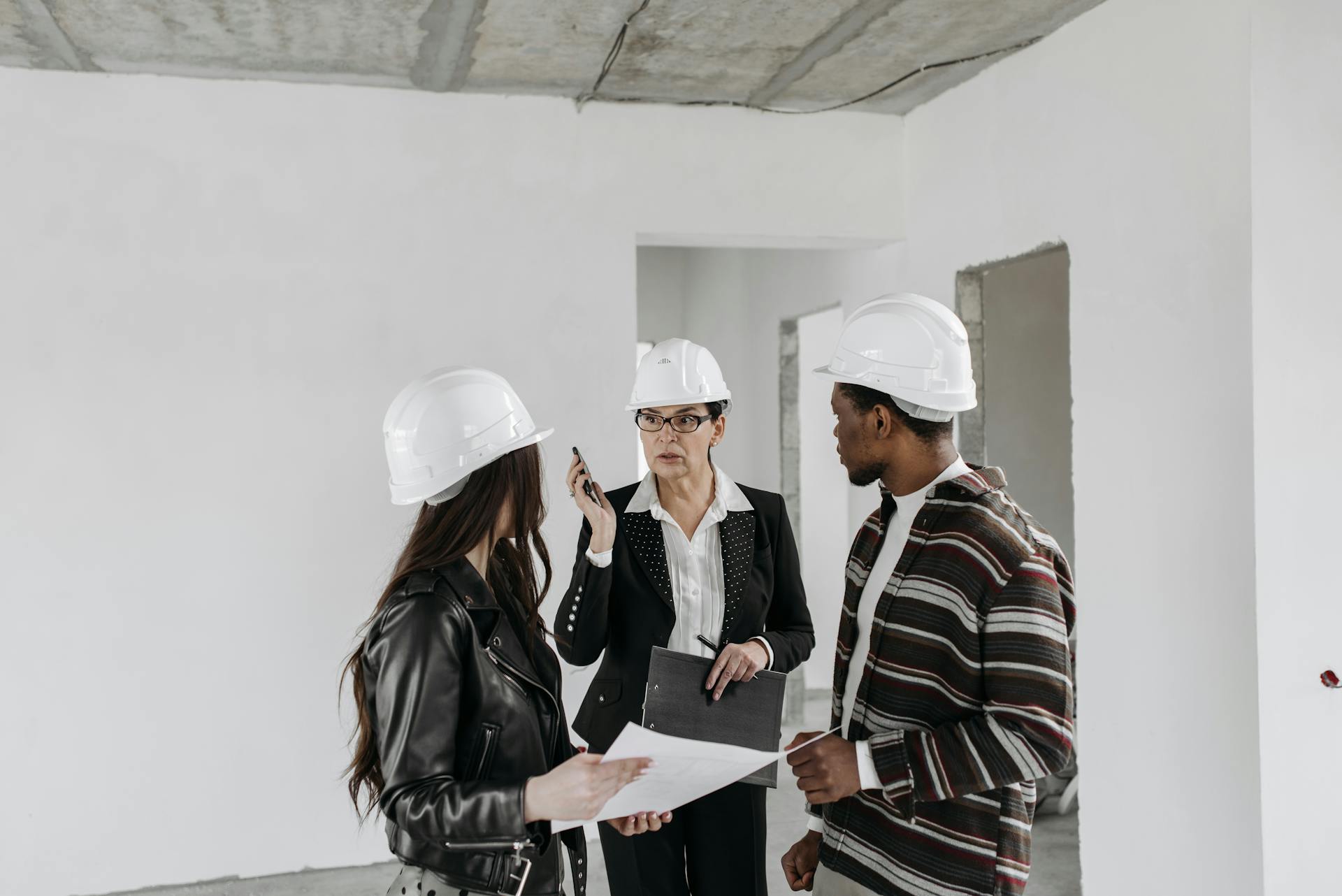 Construction professionals reviewing project plans inside a building site.