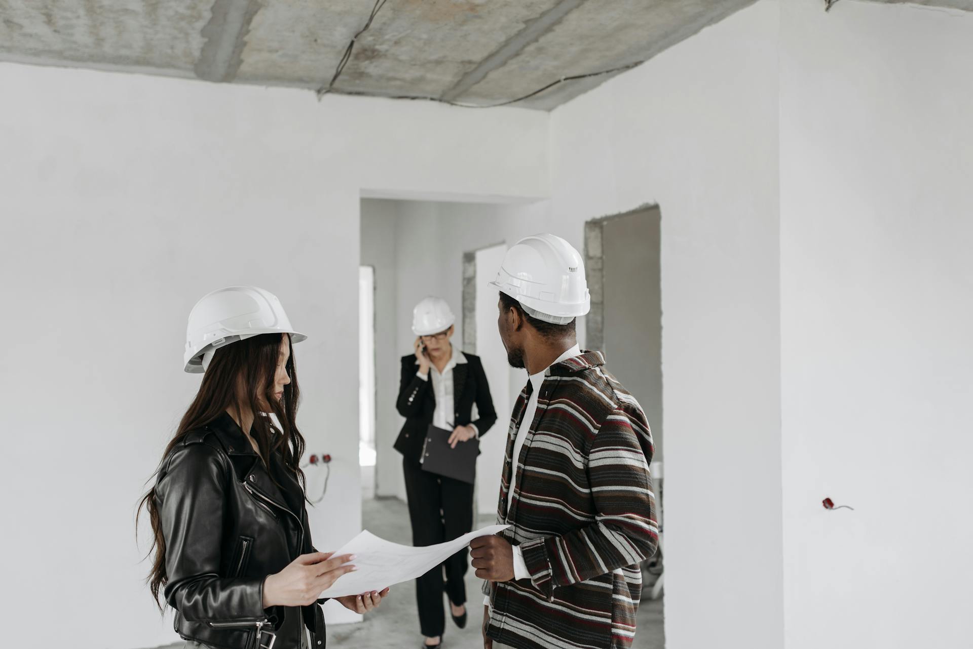 Diverse construction team in hard hats reviewing blueprints inside a building project.