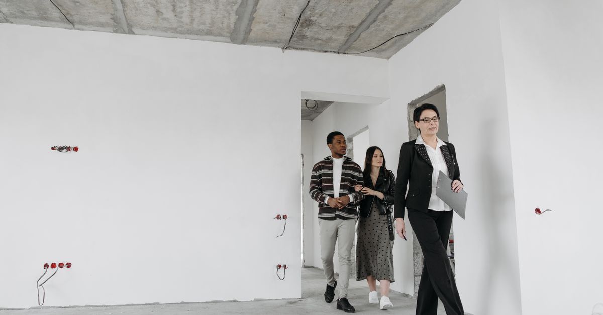 Real estate agent showing an unfinished house to potential buyers during a viewing session.