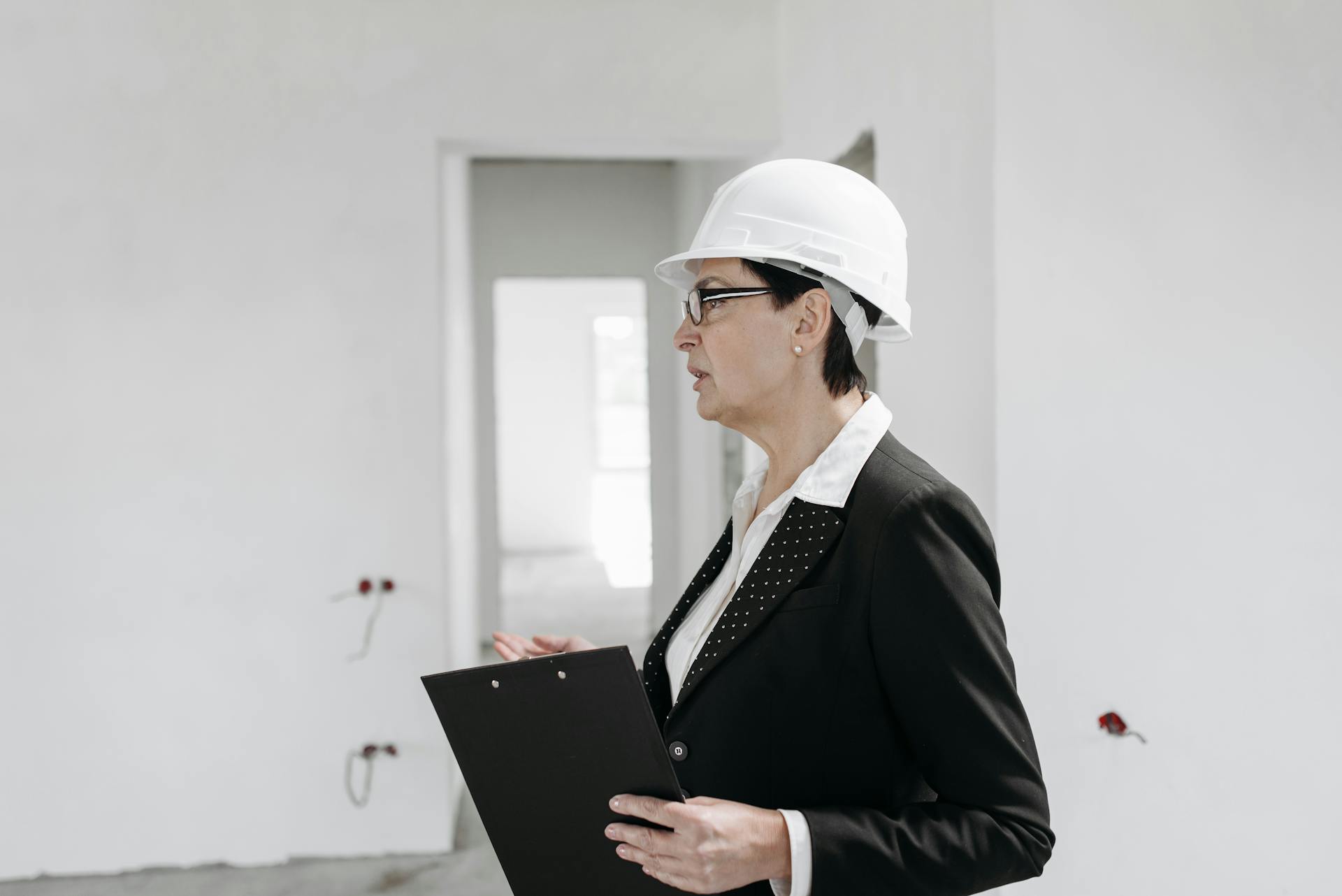 Professional female engineer inspecting a construction site with clipboard and helmet.