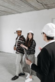 A diverse team wearing hard hats inspecting an empty room at a construction site.