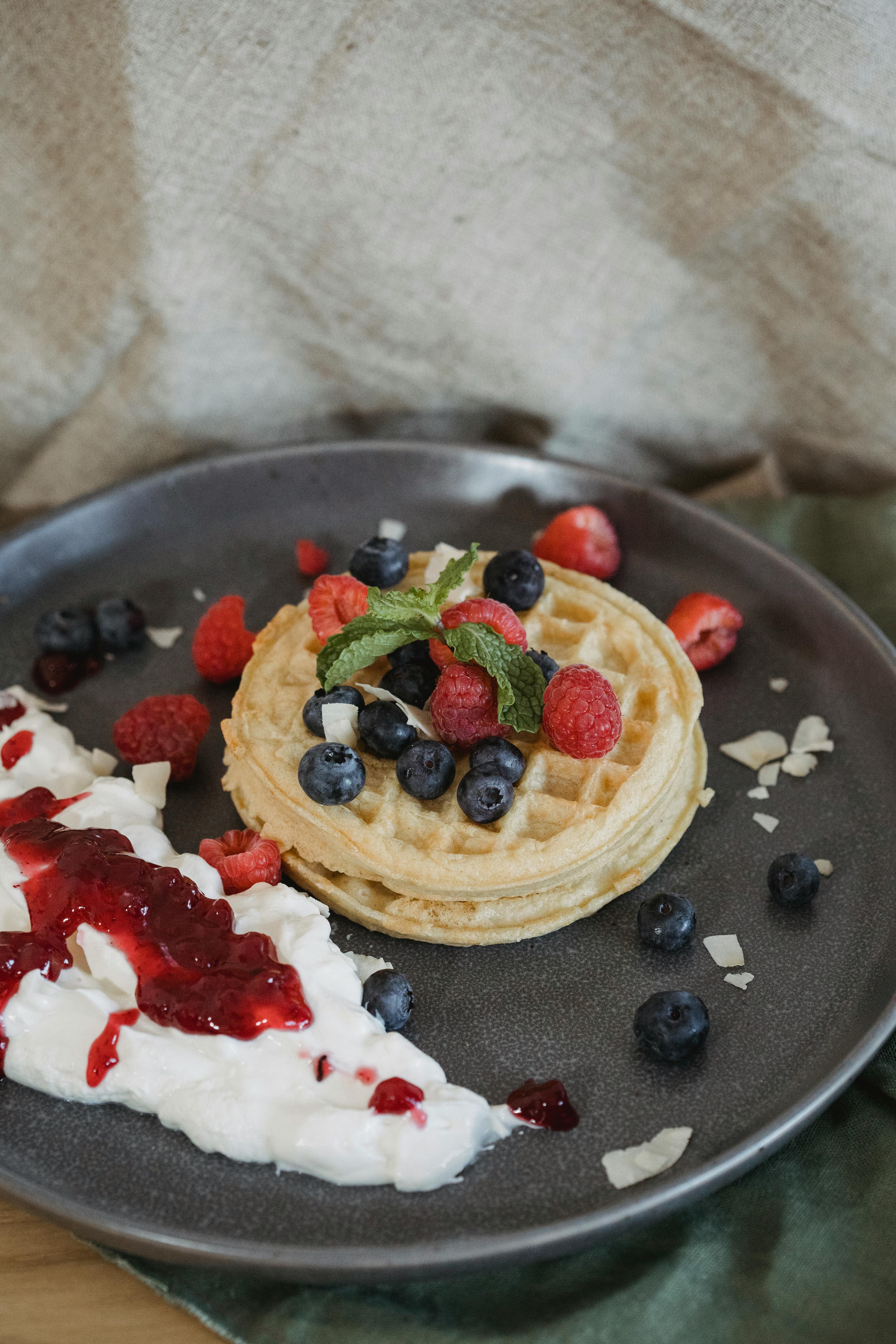 close up of waffles with fruit and whipped cream