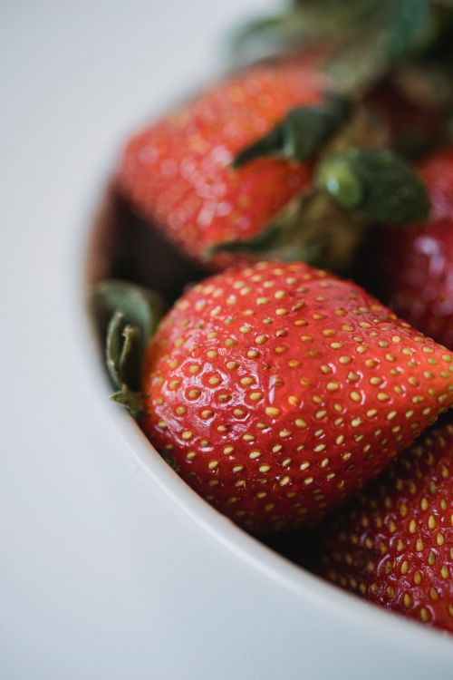 Free Close-up of fresh, ripe strawberries in a white bowl highlighting their juicy texture and vibrant color. Stock Photo