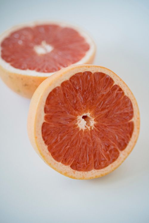 Free Close-up of fresh, juicy grapefruit halves placed on a white background. Stock Photo