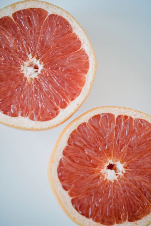 Free High-quality image of two vibrant grapefruit halves showcasing freshness and healthy eating. Stock Photo