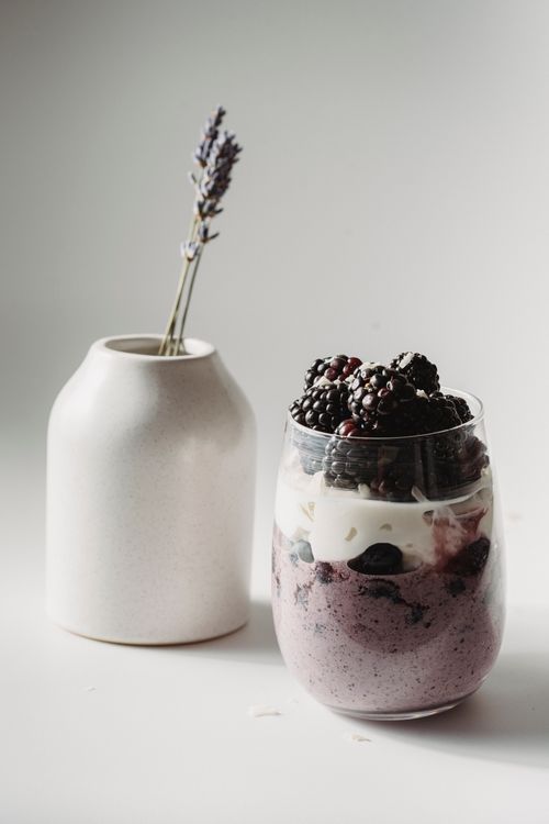 Free Elegant blackberry yogurt parfait with lavender vase on a minimalist background. Stock Photo