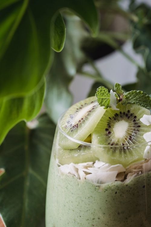 Free Delicious kiwi smoothie garnished with mint and coconut flakes for a healthy treat. Stock Photo