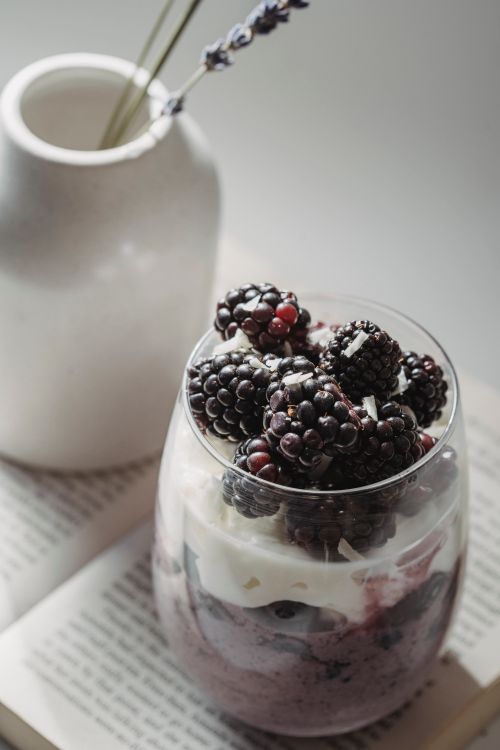 Free A close-up of a blackberry yoghurt parfait with whipped cream in a glass, styled elegantly. Stock Photo