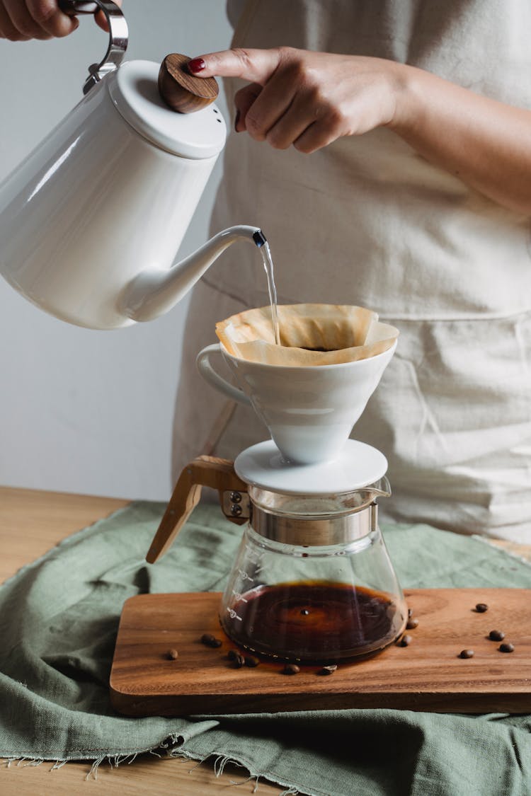 Hand Pouring Water On White Ceramic Cup With Cone