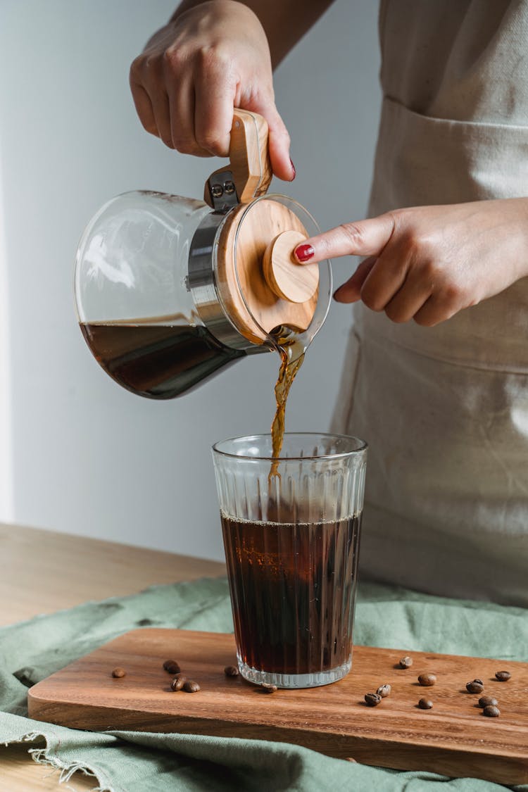 Hand Pouring Black Coffee In Clear Glass