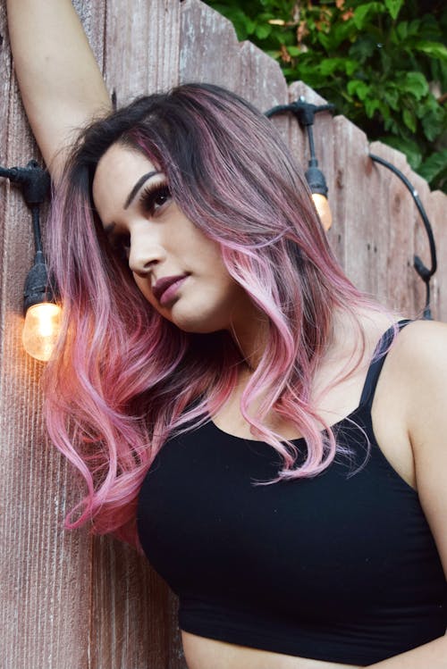 Free Dreamy woman with pink hair against wooden fence Stock Photo