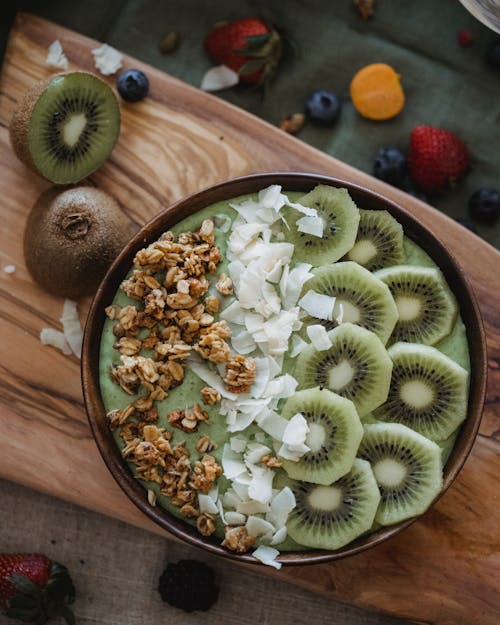 Slices of Kiwi Fruit with Nuts and Cream on Brown Bowl