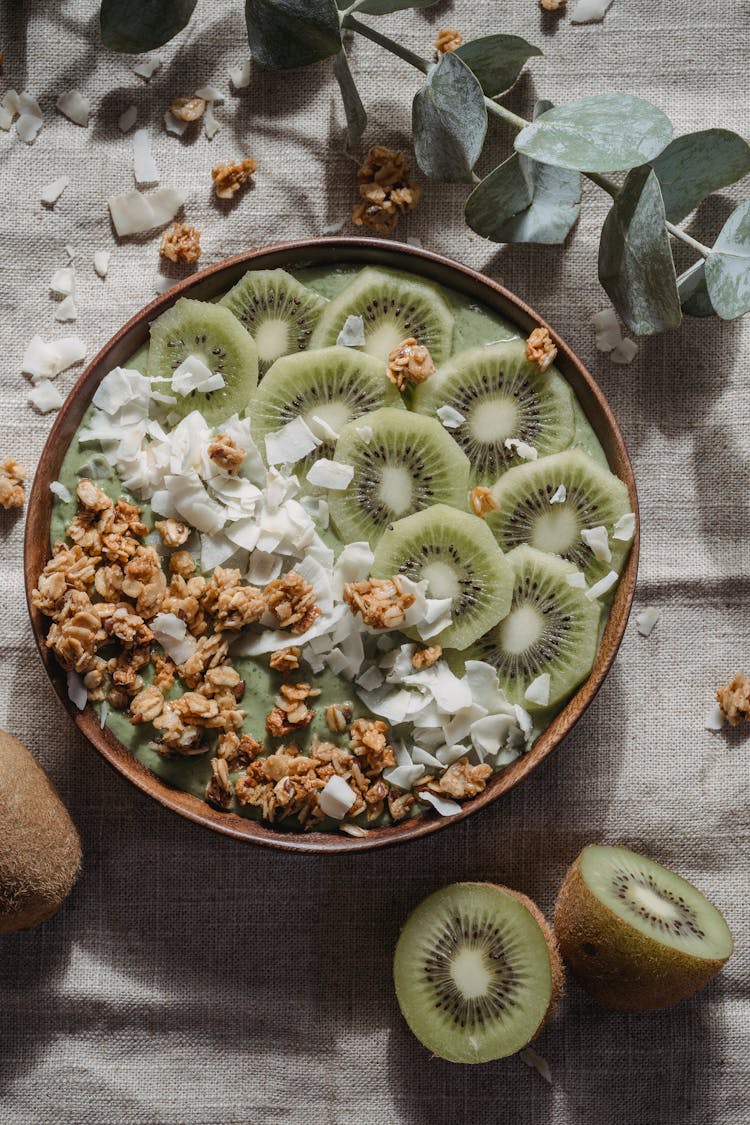 Slices Of Kiwi Fruit With Nuts And Cream On Bowl