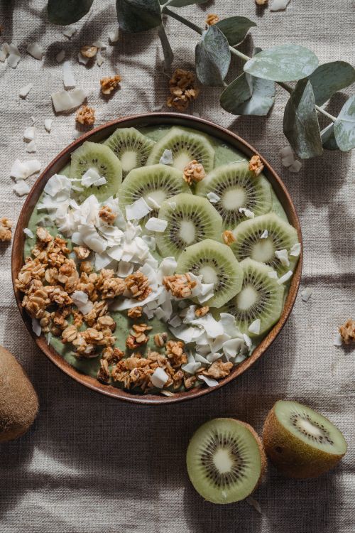 Free Top view of a healthy bowl with kiwi slices, granola, and coconut on a textured background. Stock Photo