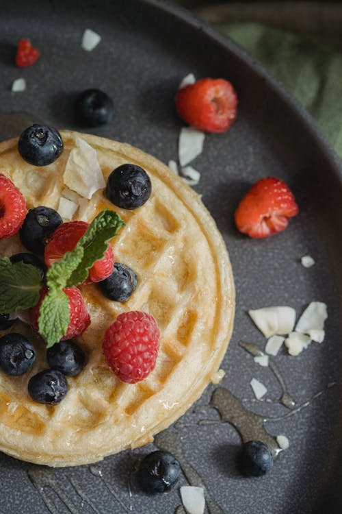 Raspberries and Blueberries with Mint Leaves on Top of Waffle