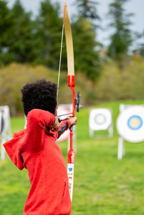 Shallow Focus Photo of a Boy in Red Hoodie Practicing Archery