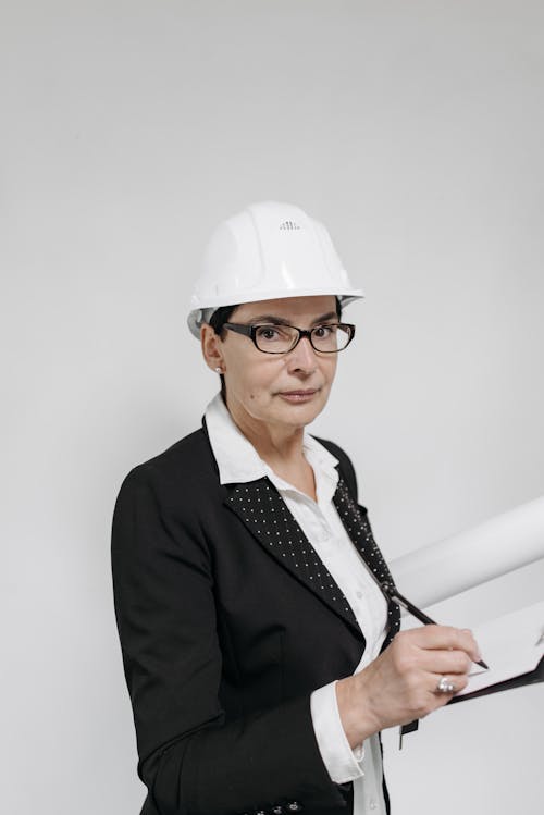 Woman in a Suit and White Helmet Holding Papers