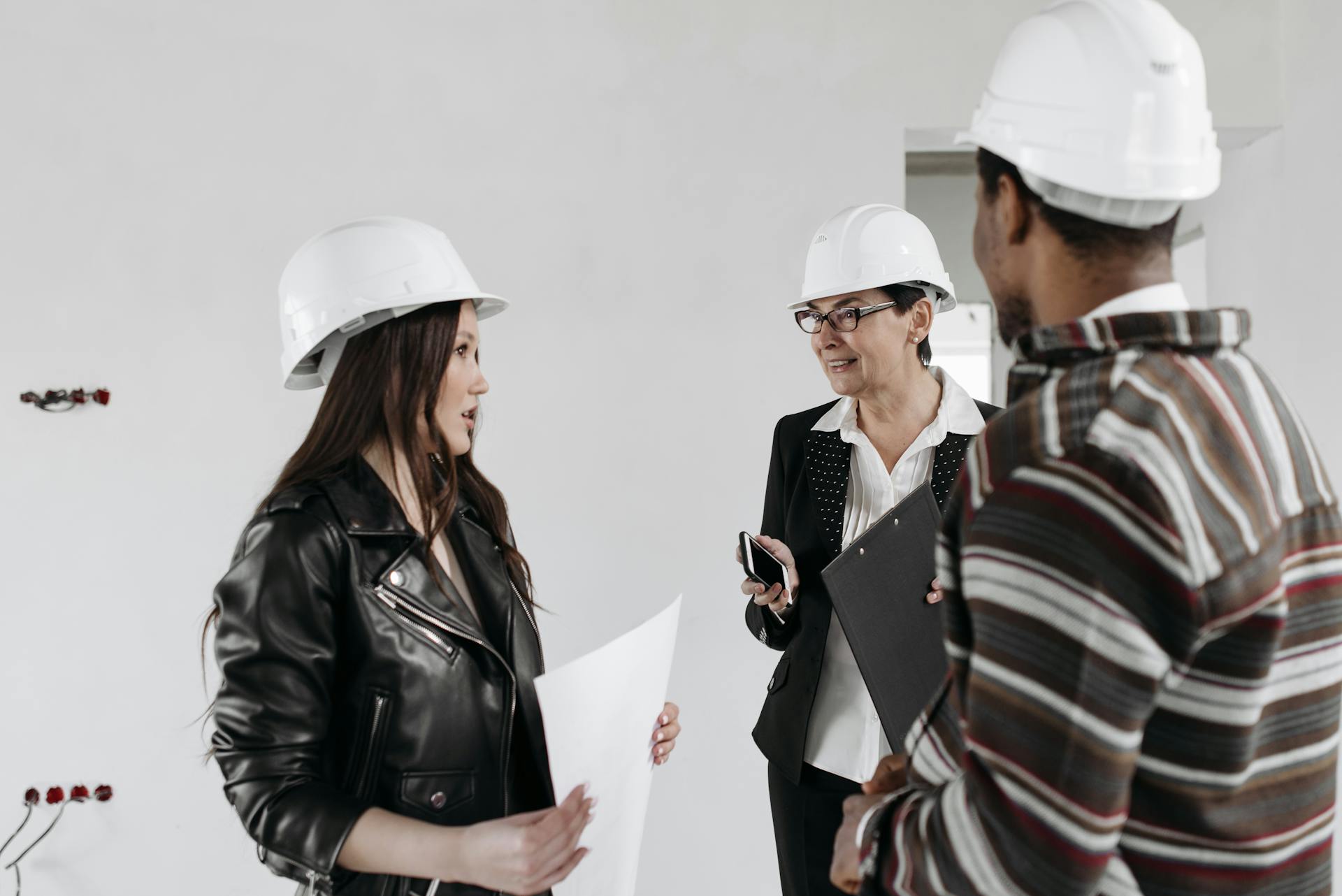 Professional team of architects in hard hats discussing project plans inside a building.