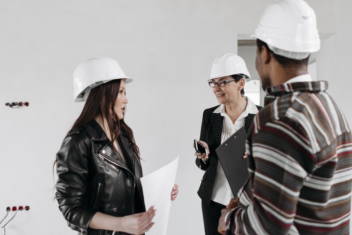A design team in hard hats reviewing project plans inside a building under construction