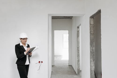 Woman in Black Suit Standing Beside White Wall in 