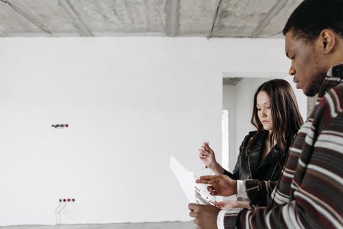 Free A couple discusses home renovation ideas in an empty room with white walls. Stock Photo